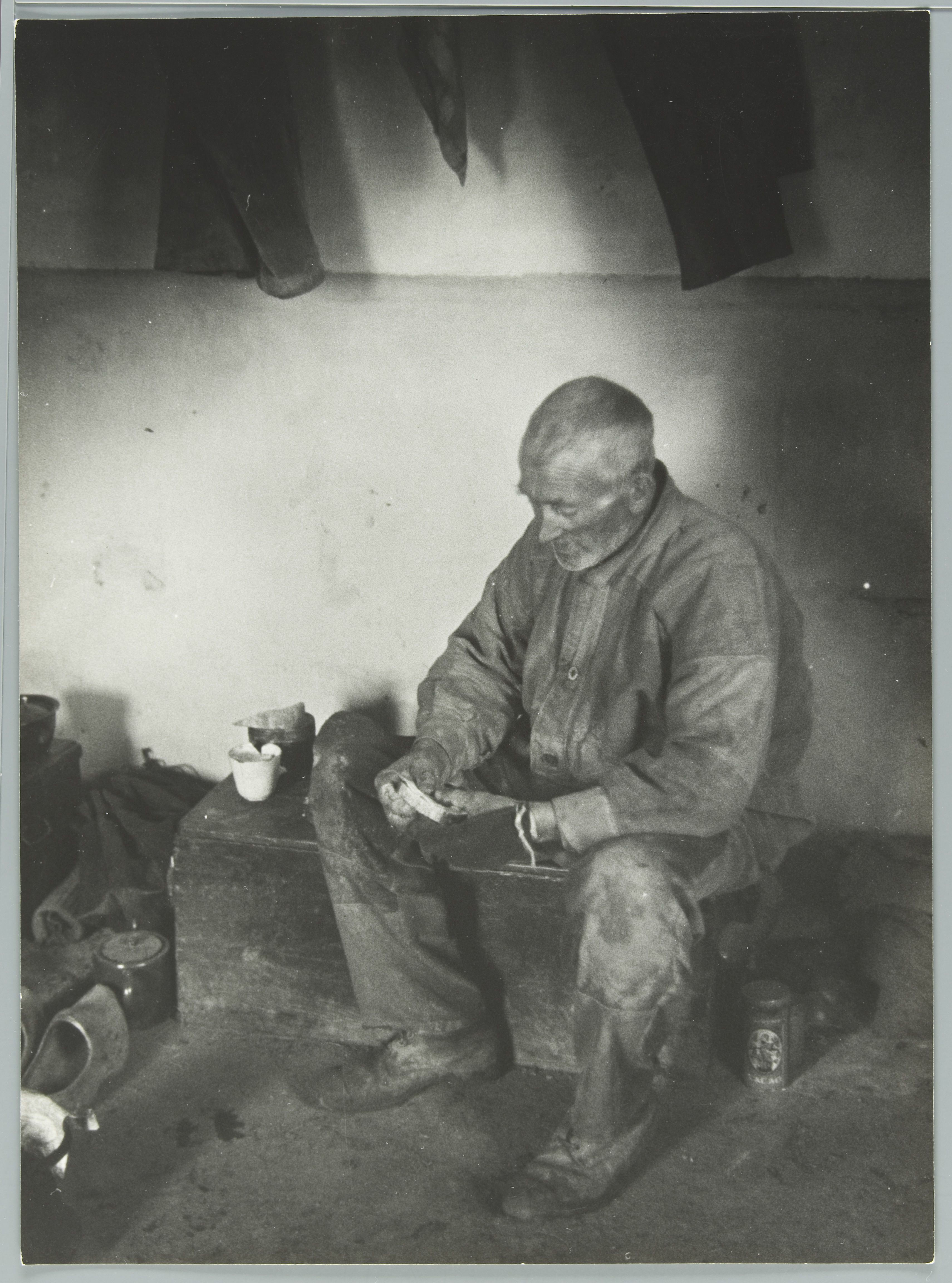 Omschrijving: (Land)arbeider aan het schaften [in één van de hutten] in de Biesbosch. [1936].